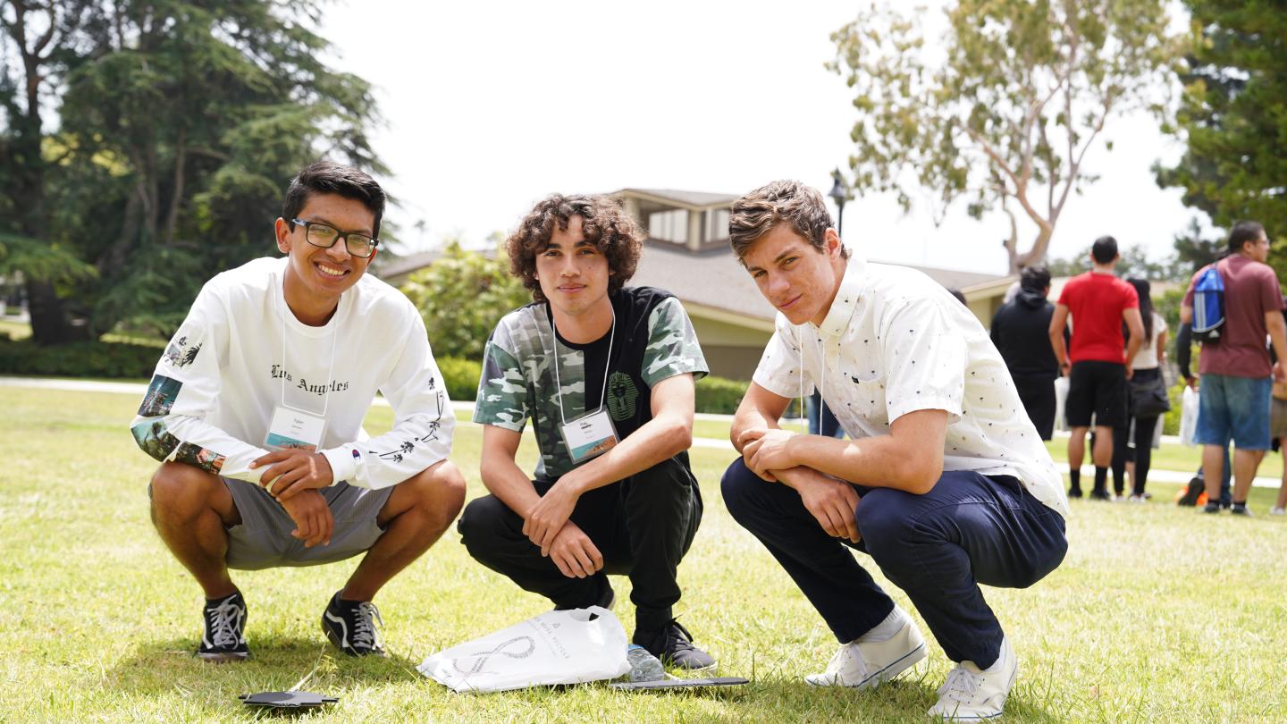 three people crouched down on a lawn