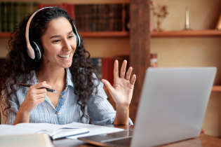 Woman smiling and working on laptop with headset