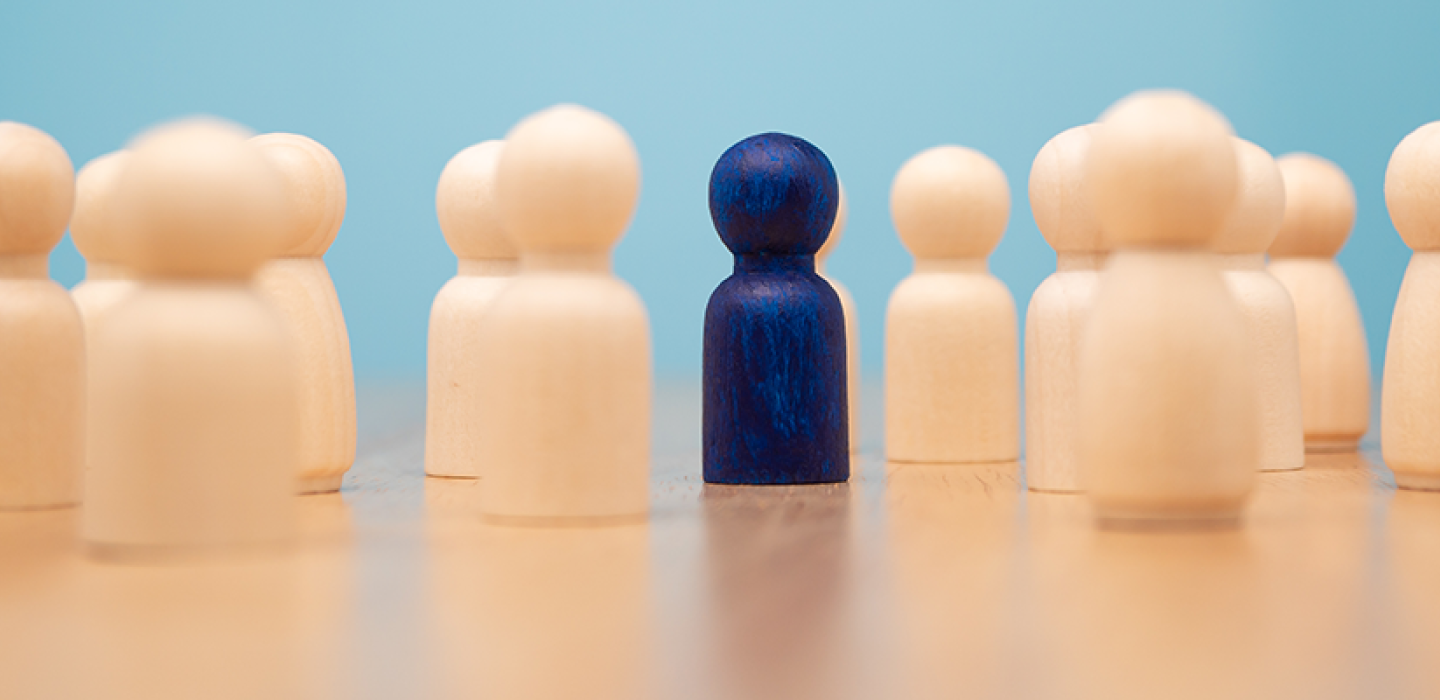 Wooden figure standing with team to show influence and empowerment